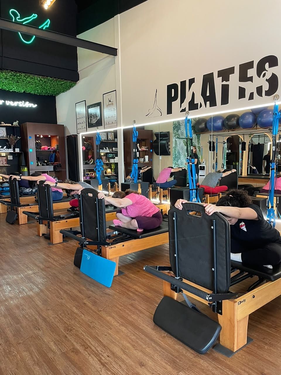 Alumnas sentadas en el Reformer estirando la espalda hacia delante, apoyadas en la barra