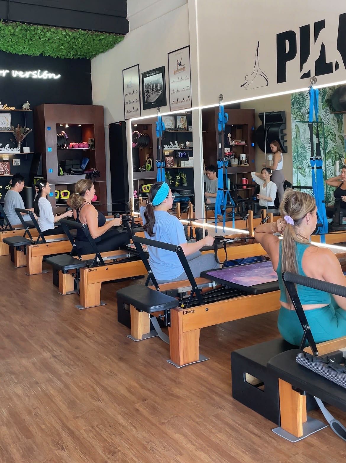 Alumnos sentados en las máquinas Reformer tirando de las correas durante una clase grupal