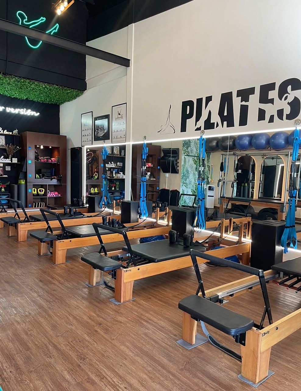 Sala del estudio con varias máquinas Reformer de madera, espejos y bandas azules colgadas