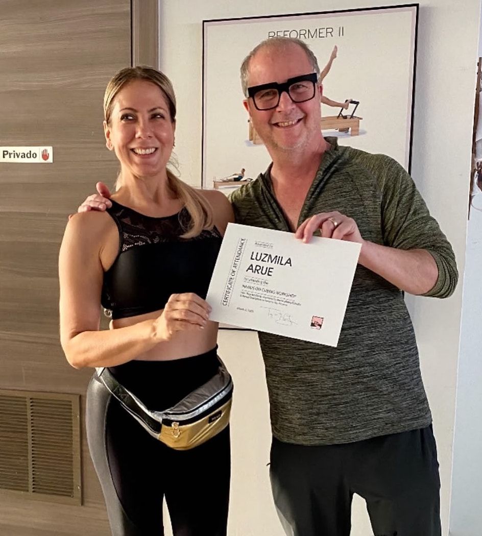 Luzmila sostiene su certificado junto al formador internacional de Pilates Troy McCarty